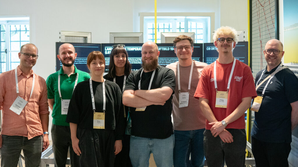 Projektteam von 3e8, der Stadt München und des Architekturmuseums München gemeinsam vor den Datenvisualisierungs-Bildschirmen der Installation Mobile Data Soil beim Festival der Zukunft in München